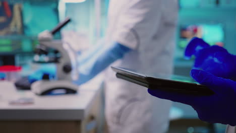 Close-up-of-scientist-writing-on-tablet