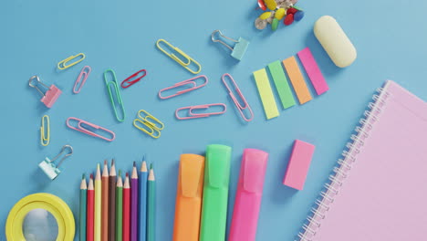 video of various office supplies, pens, paper clips, pins on blue background