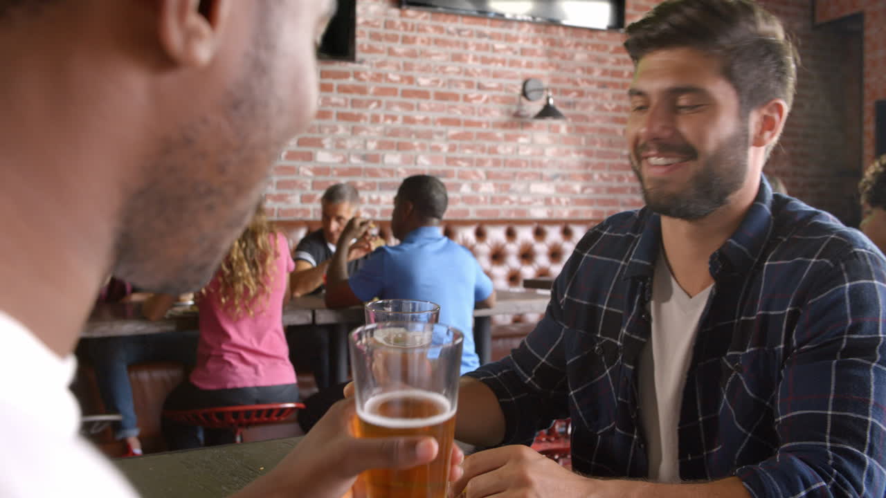 dos amigos hombres comiendo en un bar deportivo