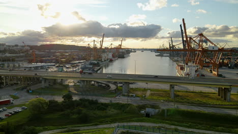 aerial view port of gdynia with container terminals and travelling vehicles on elevated road at sunset in poland