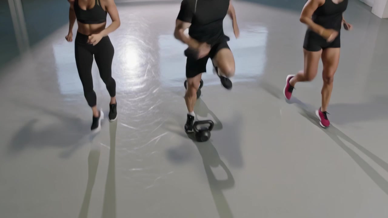 Un trio in abbigliamento sportivo si prepara a eseguire esercizi a ginocchia alte in uno studio, con kettlebell su un pavimento riflettente.
