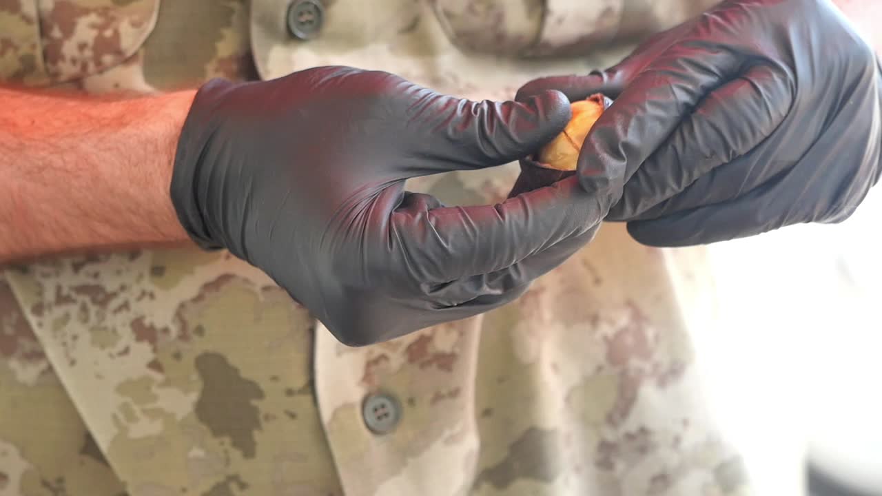 Person wearing black gloves and camouflage uniform