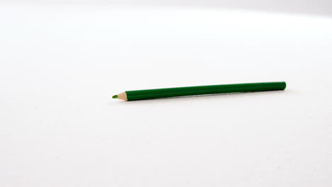 green pencil falling on white background