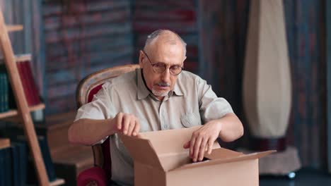 hombre anciano sonriente desempaquetando caja de cartón tienda de internet entrega de pedidos en casa rústica