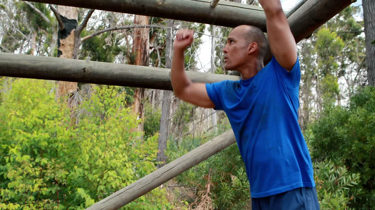 hombre en forma escalando barras de mono durante una carrera de obstáculos