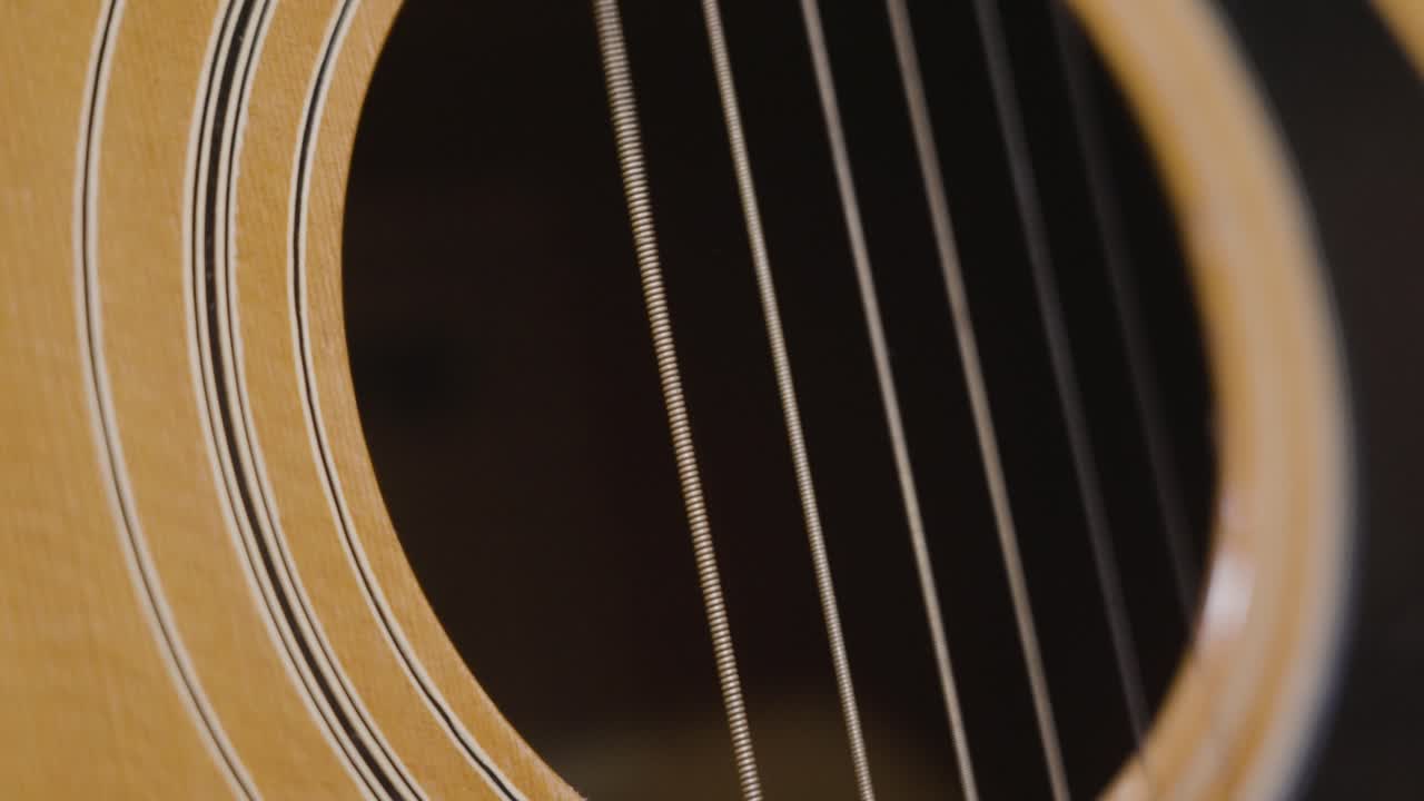 Plucking the strings of a guitar while filming in slow motion