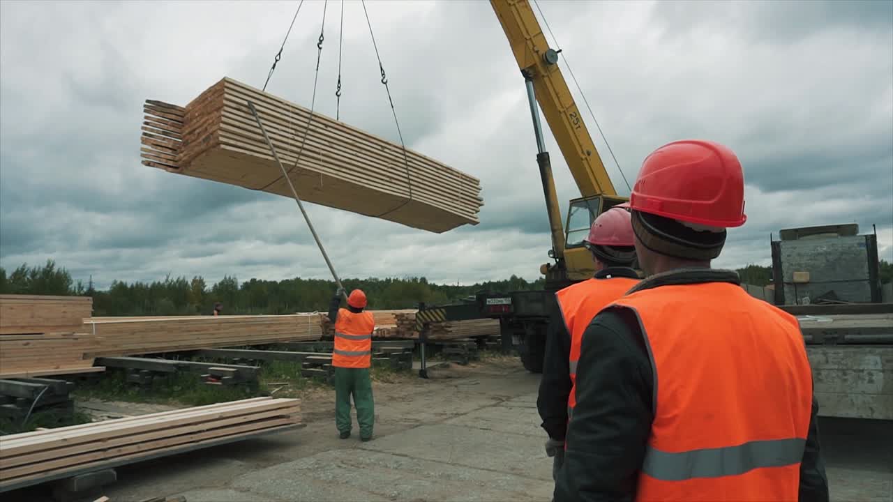 Workers loading lumber with a crane