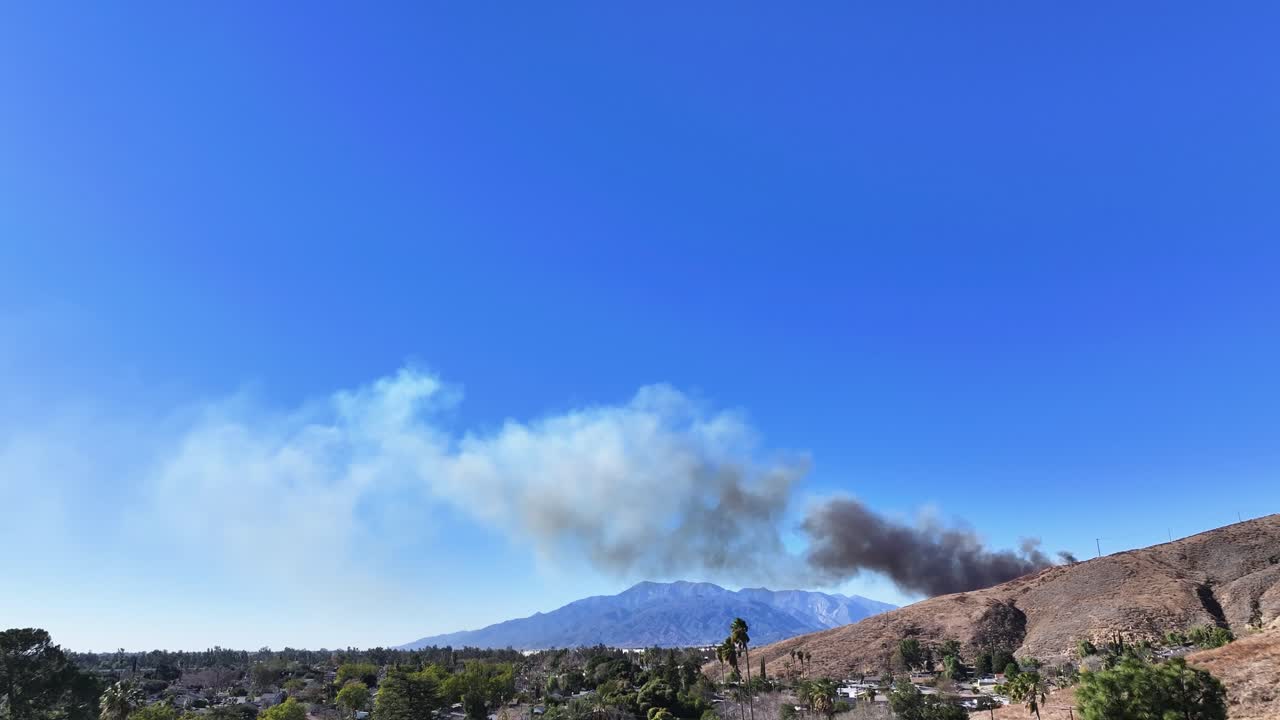 California wildfire breaking out on the horizon during blue sky day room for text on top frame STATIC SHOT