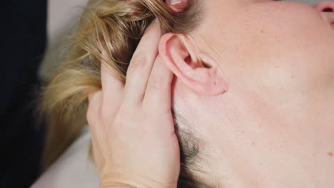 massage expert fingertips kneading side of client ear and scalp as client closes eyes and sighs in relief, gentle tension release evoking serene spa moment of deep relaxation and soothing comfort
