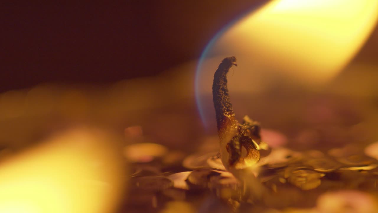 la llama dorada de una vela que ilumina la oscuridad y brilla en el viento - macro deslizante