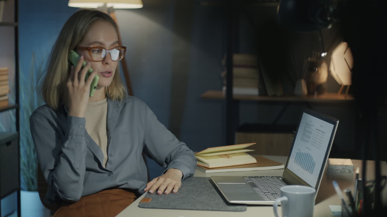 Donna al telefono, che lavora fino a tarda notte nell'ufficio di casa
