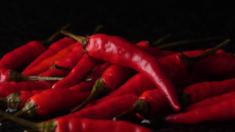 red pepper falling on group of juicy ripe peppers against black background