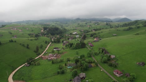 a lush green village nestled among rolling hills on a cloudy day, aerial view