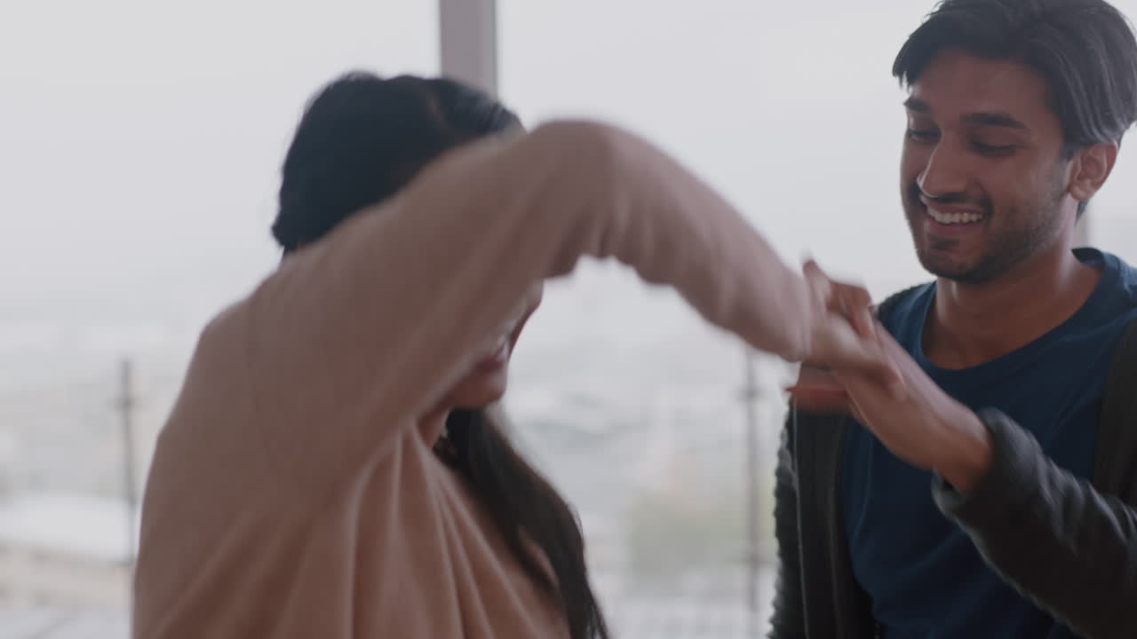 행복한 젊은 커플이 집에서 춤을 추고 성공적인 휴가를 즐기고 즐겁게 휴일에 라이프 스타일을 축하하고 거실에서 유쾌한 춤을 추고 있습니다.