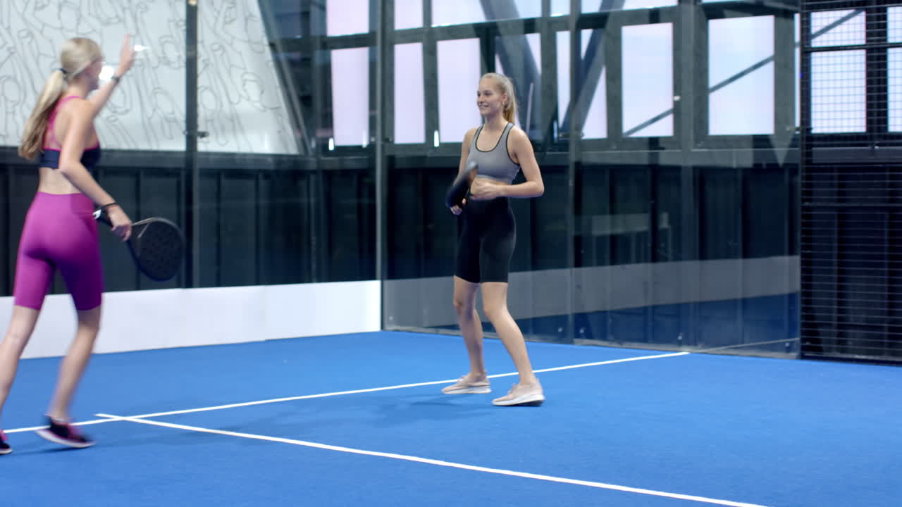Women playing padel tennis on indoor court, focused and ready for action
