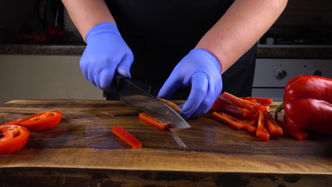 El cocinero corta pimiento morrón en una tabla de cortar