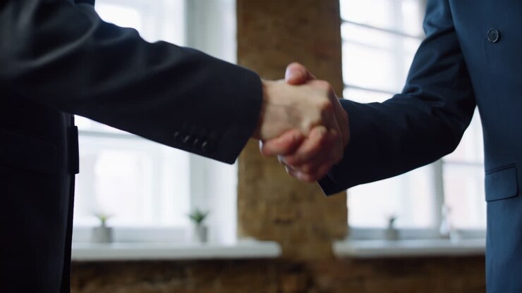 Business men shaking hands after successful signing contract in office close up.