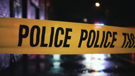 bright lights illuminate a dark street as police tape cordons off a crime scene. officers are busy managing the situation late into the night, ensuring public safety.