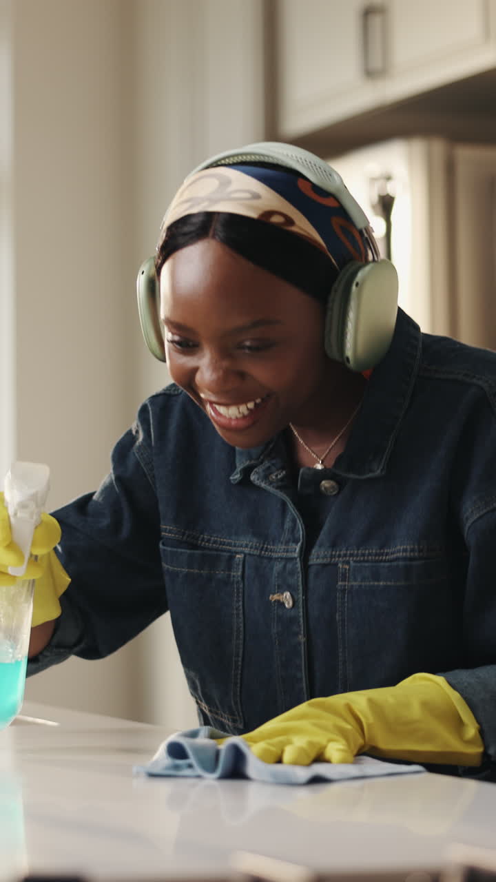 Happy Young Black Woman Cleaning Kitchen Counter with Headphones