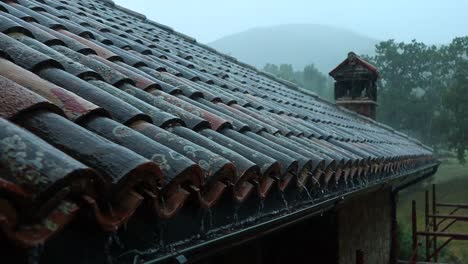 typical roof of a house in the italian countryside during a heavy storm, gutters drain rainwater