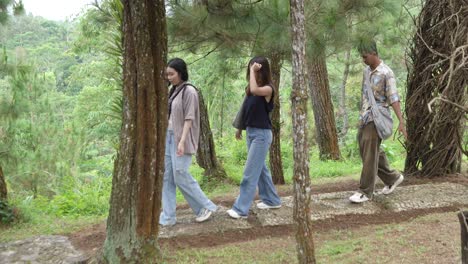 young asian friends walking on forest footpath in nature