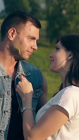 close view young brunette woman with wristwatch and golden earring runs green wheat on man cheek and chin