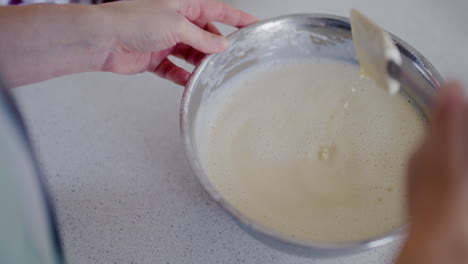 woman checking pancake batter density with plastic dough spatula