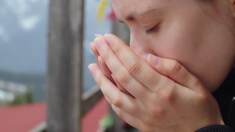 retrato lateral cercano de una mujer joven que inhala el aroma del té del cuenco en sus manos. niña sosteniendo una taza con hojas de té secas o hierbas medicinales oler y sonreír. productos orgánicos naturales para una buena salud