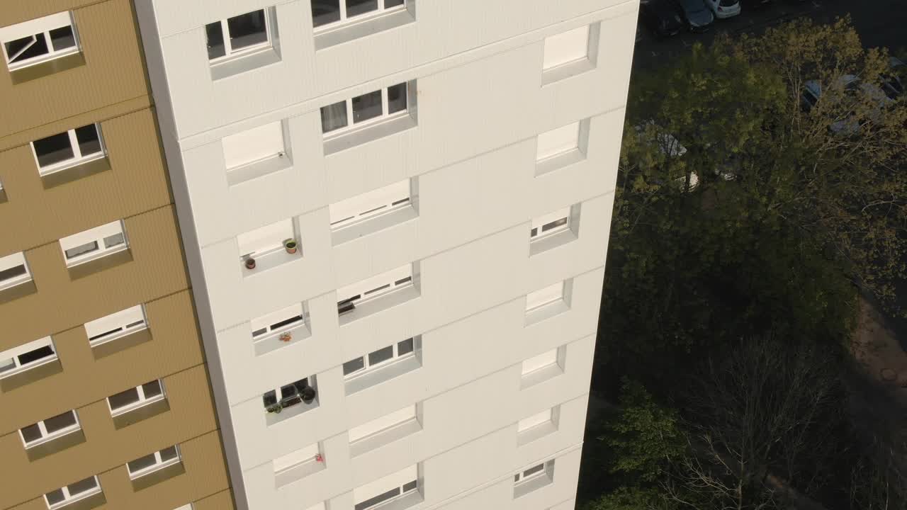 Close-up aerial drone shot focusing on the facade and windows of a modern apartment building in Nantes. Urban architecture, housing detail. France