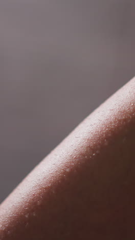 woman leg with water drops in bathroom closeup. bare lady leg covered with small droplets on light background. bathing procedures and spa at home