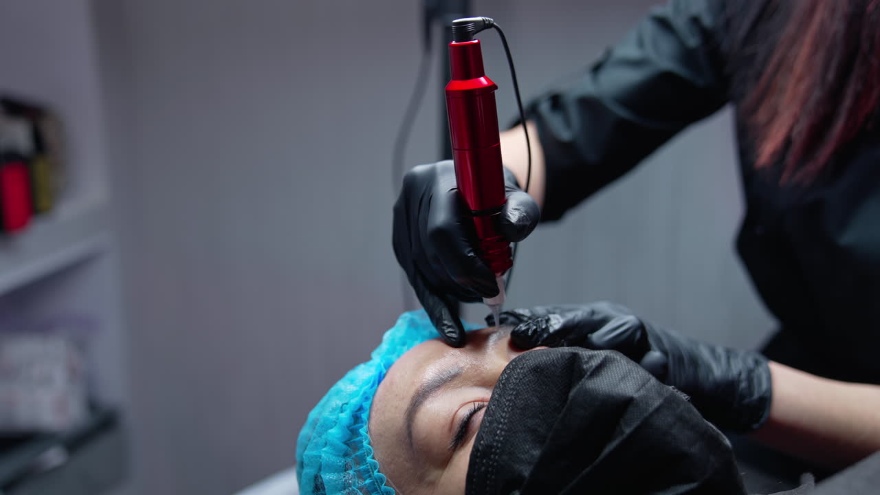 Pretty young woman making permanent beauty procedure. Cosmetic young specialist doing permanent make up.