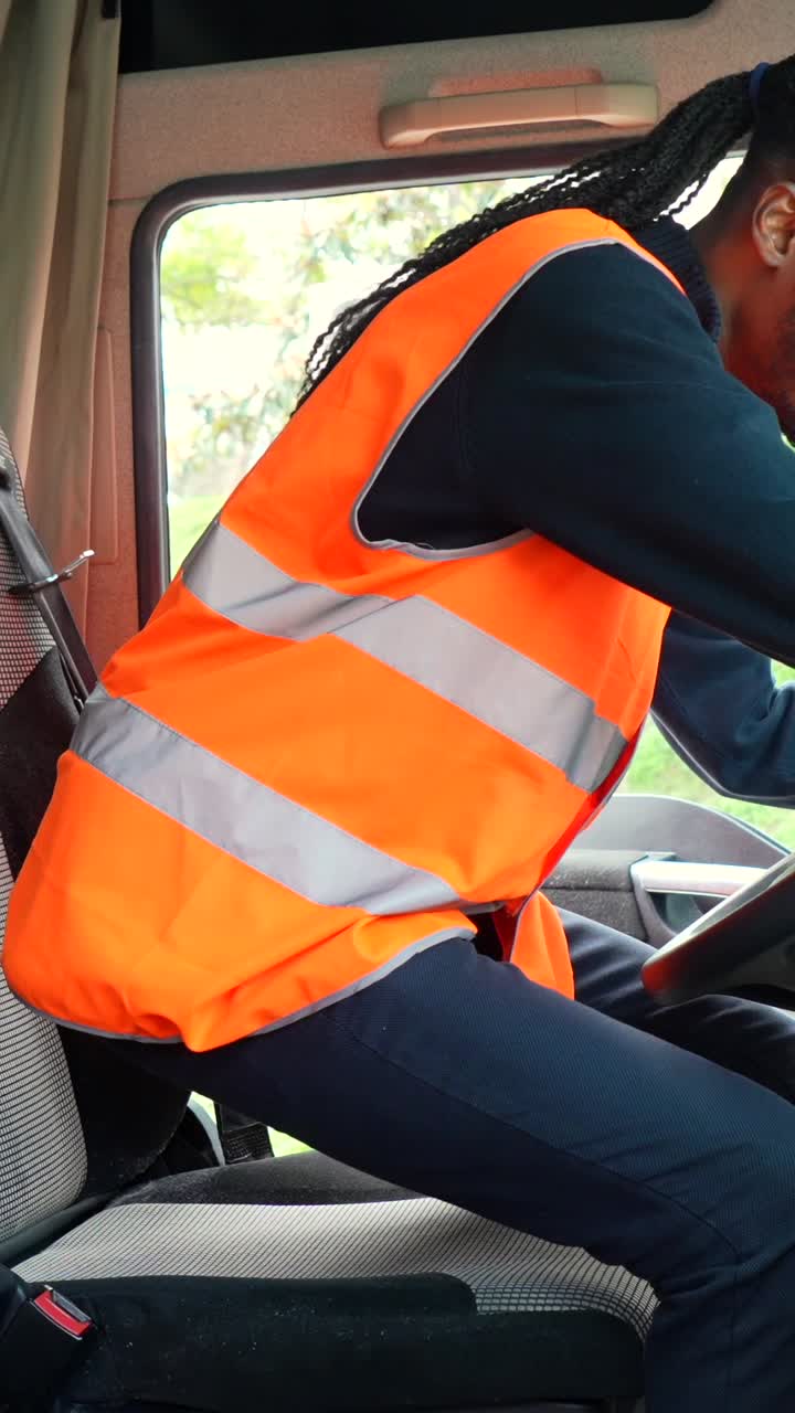 A truck driver in a safety vest driving a truck