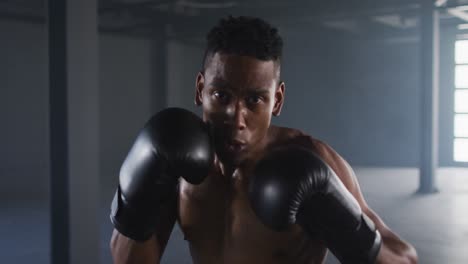 african american man wearing boxing gloves training throwing punches in empty room