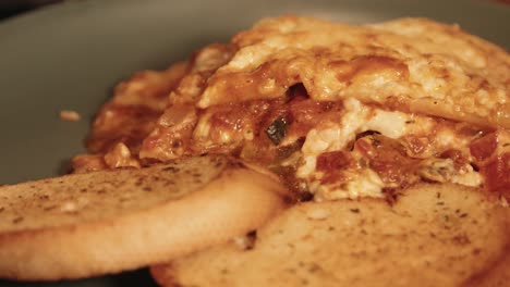 close up of hot italian lasagna with garlic bread slices