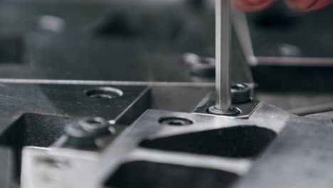 Close-up-of-a-hex-key-screwing-in-a-bolt-on-a-big-metal-components-in-the-factory