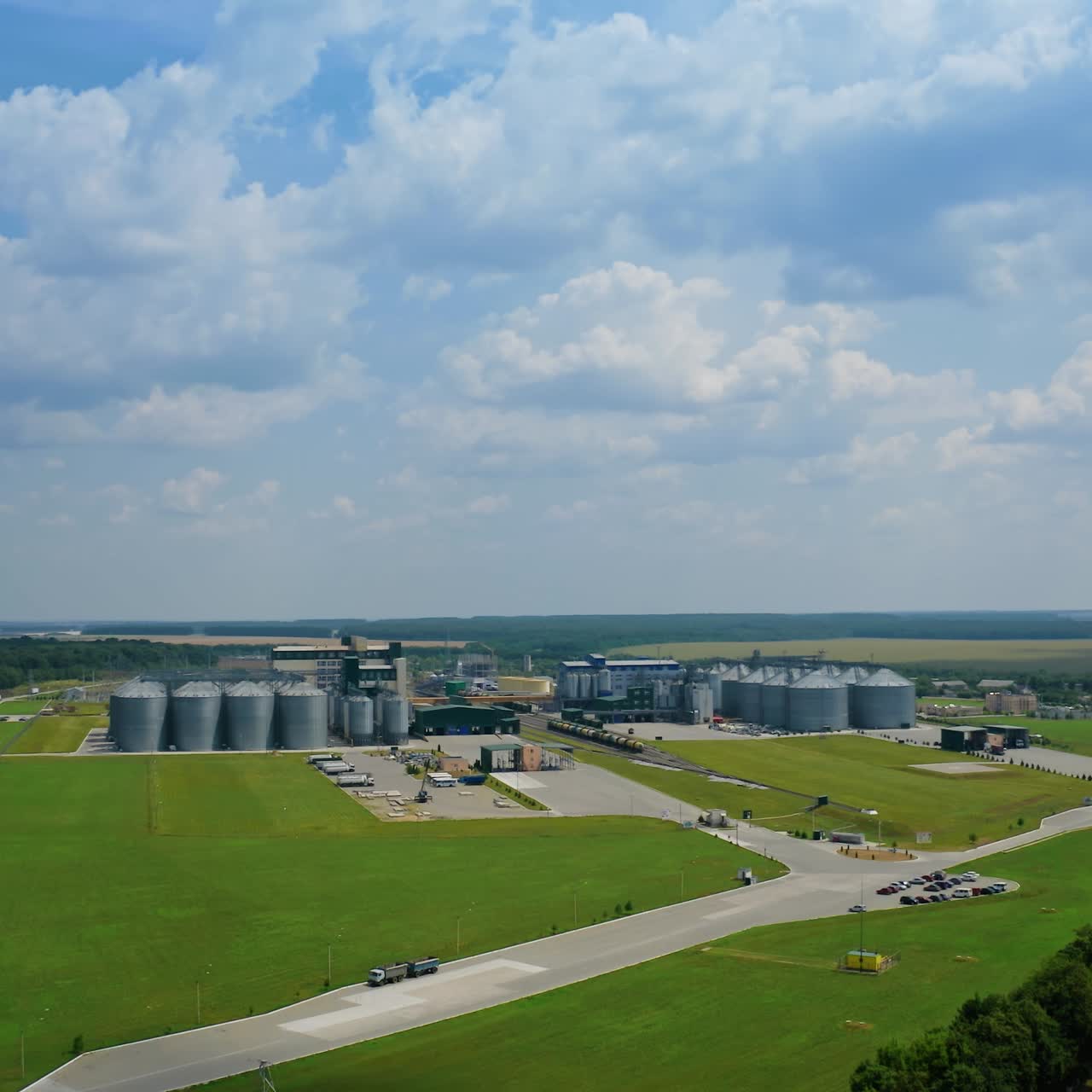 Modern factory among fields. Grain elevators for keeping agricultural products. Grain storage tank in the countryside. Aerial view
