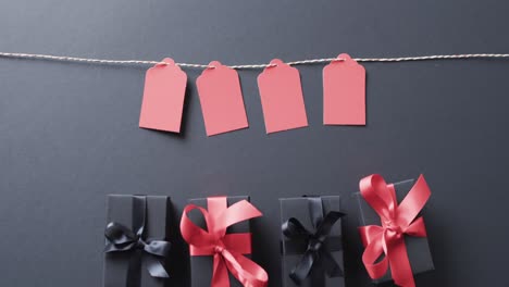 Video-of-gift-tags-on-string,-gift-boxes-with-ribbons-and-copy-space-on-black-background