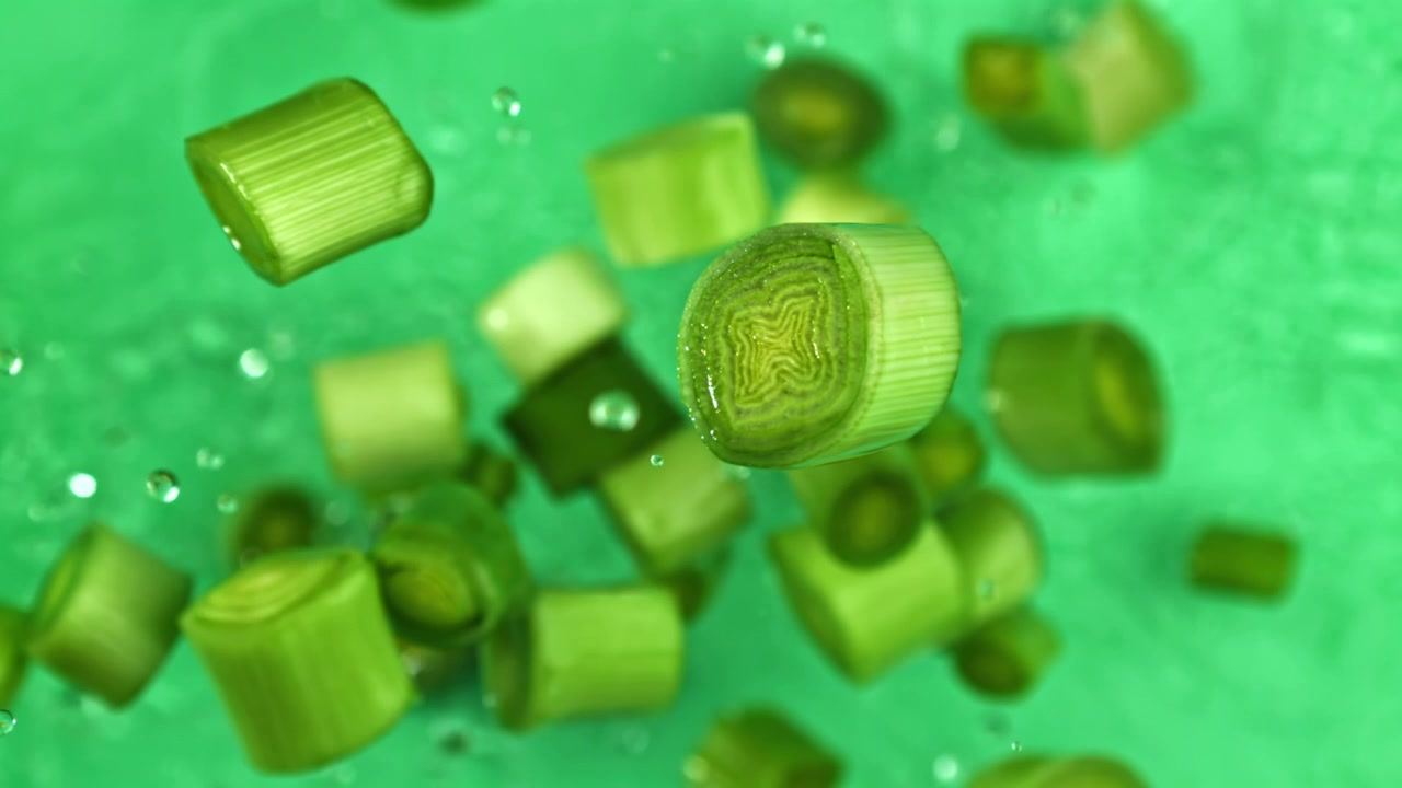 Fresh Chopped Green Onions Floating in Water on Green Background