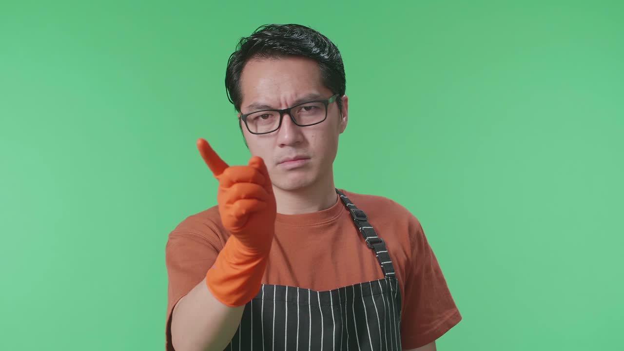 녹색 스크린 스튜디오에 서 있는 동안 손가락을 흔들고 있는 아시안 남성 집주인