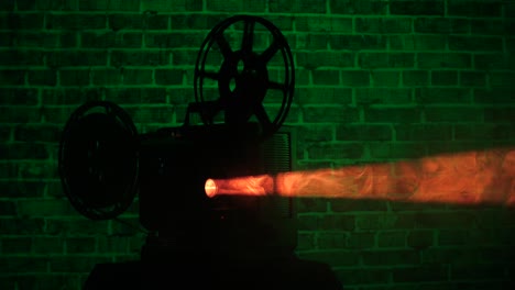 silueta de un proyector de película de 16 mm con un fondo de pared de ladrillo iluminado en verde