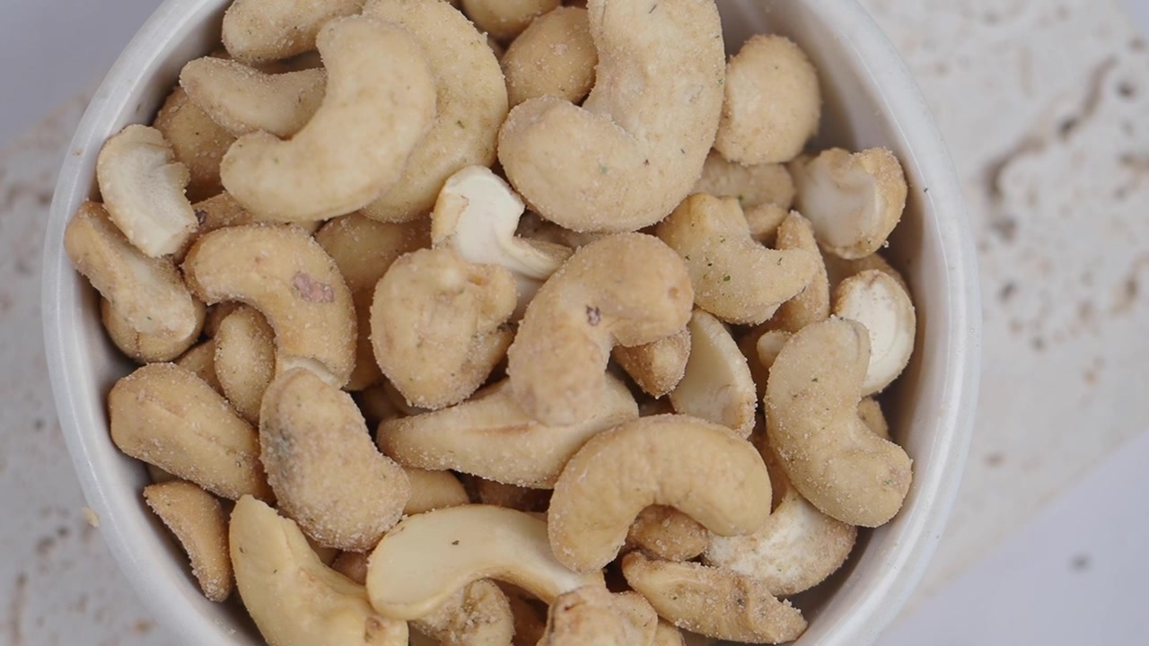 Nærbilde av ristede og krydrede cashewnøtter i en hvit skål
