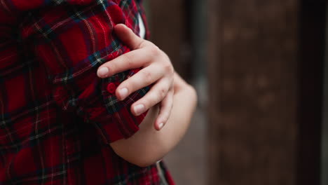 mujer abrazándose a sí misma en la terraza de la cabaña de cerca. dama congelada en camisa a cuadros roja se calienta con el abrazo de sí misma en un frío día de otoño. modelo cruza los brazos