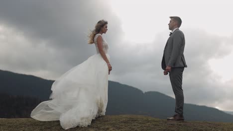 young newlyweds bride groom stay on mountain slope, making a kiss, wedding couple family in love