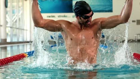 fit man raising arms in the pool