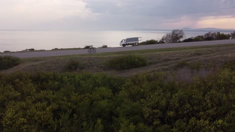 4k 30fps cyclist ride on a road alongside the sea in a beautiful epic setting landscape