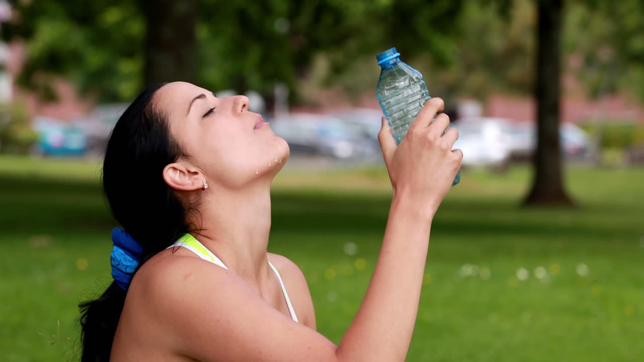una bonita morena bebiendo de una botella de agua