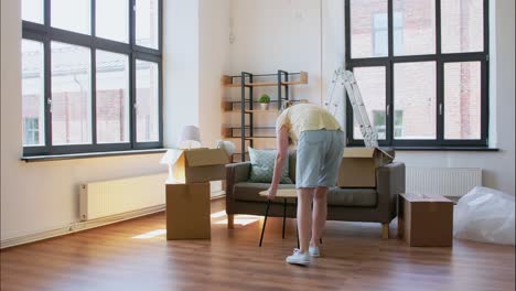 Happy-Woman-Unpacking-Boxes-and-Moving-to-New-Home.moving,-people-and-real-estate-concept-happy-smiling-woman-with-box-unpacking-things-at-new-home