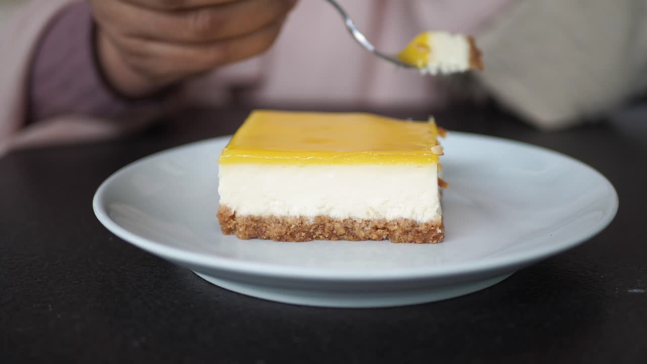 persona comiendo una rebanada de pastel de queso de limón