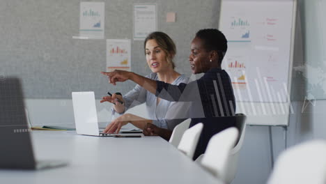 Animation-of-graphs,-loading-bars-and-map-over-diverse-female-coworkers-discussing-reports-on-laptop