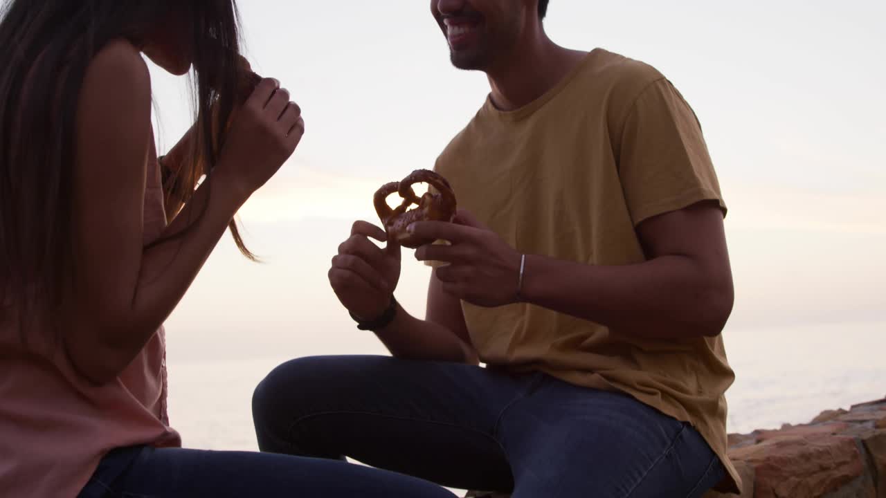 man and woman sharing pastry romantically causing social media icons floating fading around them